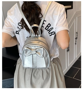 Detailed view of silver mini backpack with large bow detail and metallic leather finish
