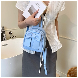 Close-up of light blue mini backpack with a large bow detail and smooth PU leather texture