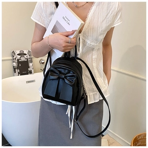 Detail of cute black mini backpack featuring a large bow and matte leather finish
