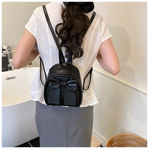 Mini black bow backpack for women in smooth PU leather shown on a model's back