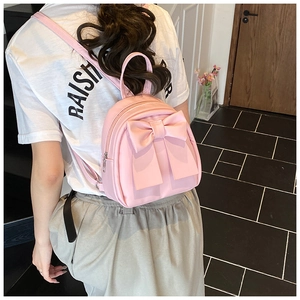 Rosa Mini-Rucksack mit großer Schleife, getragen von einem Modell in modernem Ambiente