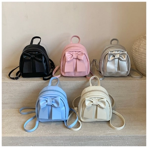 Detailed view of trendy mini backpacks with large bows in five colors on stone steps