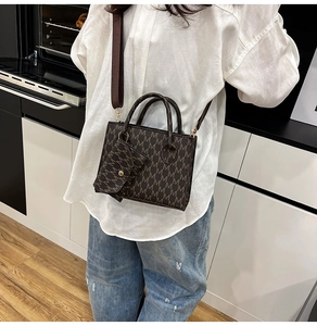 Dettaglio borsa shopper marrone con monogramma, tracolla larga e mini portamonete