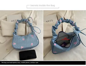 Detail of floral denim handbag with pleated handle showing interior capacity and main pocket