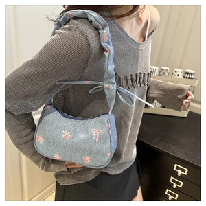 Detail of light blue denim hobo bag featuring pink floral print and ruffled shoulder strap