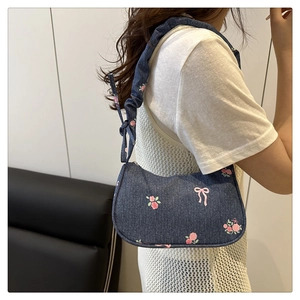 Detail of sweet denim bag with rose embroidery and ruched strap on model