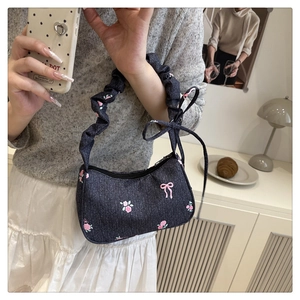 Detail of sweet blue denim underarm bag with pink floral embroidery and ruffled strap