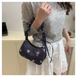 Detail of blue denim bag featuring pink rose embroidery and a scrunchie style handle