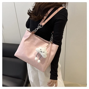 Detailed shot of pink crocodile-embossed tote bag with a cute cloud plush pendant