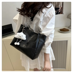 Detail of black geometric tote bag featuring silver chain strap and white cloud charm