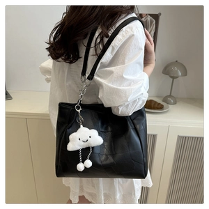Detail of black patchwork shoulder bag featuring a cute white cloud plush pendant