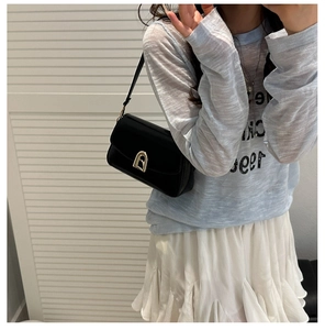 Gros plan d'un sac sous le bras noir brillant avec boucle dorée sur un mannequin