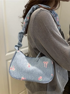 Denim underarm bag with floral rose prints and bow details featuring a ruched strap