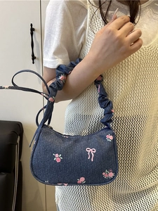 Blue denim underarm bag featuring pink rose and bow prints with a stylish ruched strap