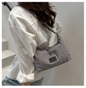Détail du sac bandoulière gris en nylon avec double fermeture éclair et étiquette de marque