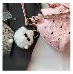 Details der rosa Tasche mit Schmetterlingsmuster und flauschigem Monster-Anhänger