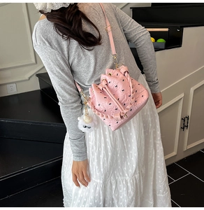 Rosa Kordelzug-Beuteltasche mit schwarzen Schleifen und Plüsch-Anhänger am Modell