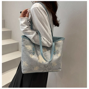 Detail of grey-blue tote bag featuring vintage floral patterns and golden rivets