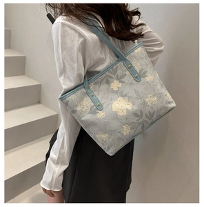 Close-up of blue floral tote bag with gold rivet details and premium PU leather finish