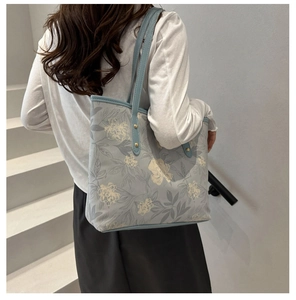 Detail of light blue floral tote bag with white flowers and double shoulder straps