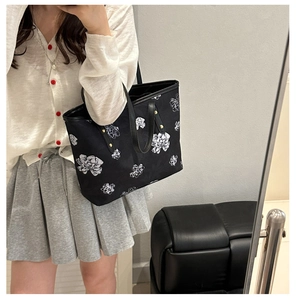 Detail of floral canvas tote bag with black leather handle and gold rivet hardware