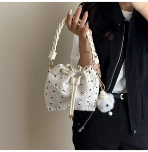 Detail der weißen Beuteltasche mit schwarzen Schleifen und gewebtem Griff mit Bommel