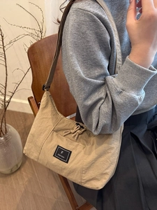 Sac bandoulière minimaliste en nylon kaki avec étiquette noire et sangle réglable