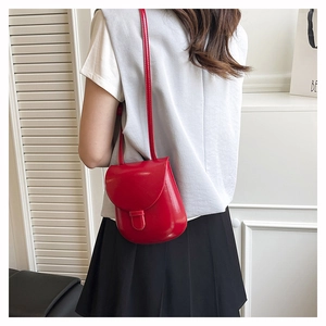 Detailed back view of a red vintage-style mini saddle crossbody bag on a female model