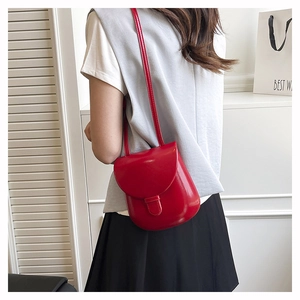 Model wearing a red patent leather mini saddle bag with a gray vest and black skirt
