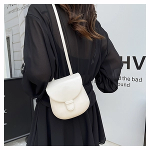 Close-up of a white minimalist saddle bag showing the adjustable strap and buckle detail
