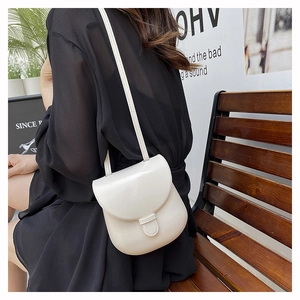 Minimalist cream white crossbody bag shown on a model with neutral background decor