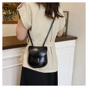 Detail of a black leather saddle bag for women worn over the shoulder as a crossbody phone bag