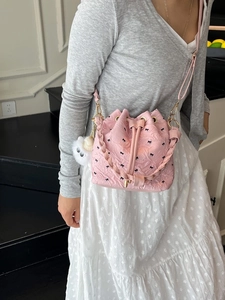 Rosafarbene Eimertasche mit Schleifenmuster, gewebtem Griff und Kettengurt am Modell