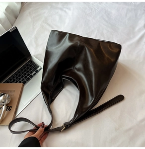 Detail einer dunkelbraunen Shopper-Tasche mit verstellbarem Gurt und Goldmetallschnalle