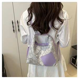 Detail of purple jacquard handbag with geometric patterns worn on shoulder by model