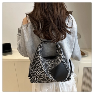 Dettaglio di texture geometrica argento con fiori bianchi su borsa a mano in pelle nera