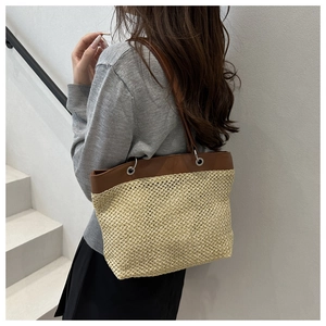 Detailed texture of straw woven tote with premium brown leather straps and metallic eyelets