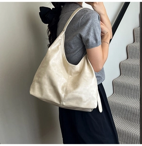 Detail einer großen cremeweißen Hobo-Tasche mit Kunstlederstruktur und weichem Falten-Design