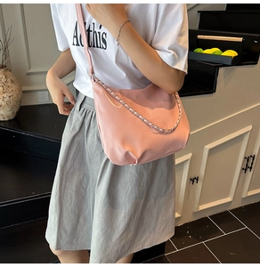 Detail of pink crescent bag with shiny PU leather texture and stylish chain strap design