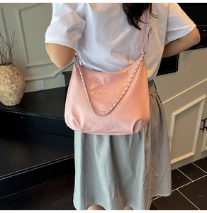 Close-up of pink glossy hobo bag with silver chain and adjustable shoulder strap