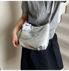 Detailed shot of silver PU leather handbag with metallic chain and white plush monster charm