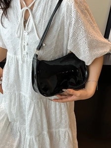 Borsa sottobraccio in pelle verniciata nera lucida con forma a mezzaluna su modella