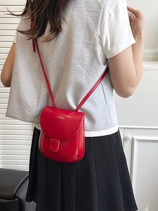 Elegant red leather saddle crossbody bag with a curved flap shown on a model