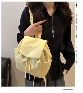 Detail of yellow nylon backpack featuring flap drawstring closure and side pockets