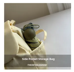 Detail view of the side storage pocket on light yellow backpack holding a folding umbrella