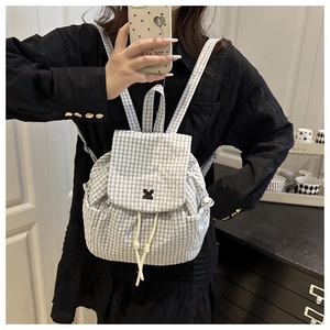 Detail of black and white plaid backpack with drawstring closure and front flap design