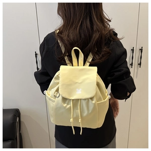 Detail of light yellow nylon backpack with drawstring closure and stylish flap design