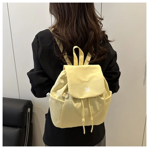 Lifestyle shot of light yellow checkered backpack on model with adjustable drawstrings