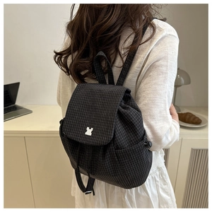 Detail of checkered drawstring backpack with metal buckle and side pocket on model