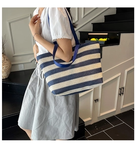Dettaglio della borsa tote tessuta a righe bianche e blu con manici in pelle blu